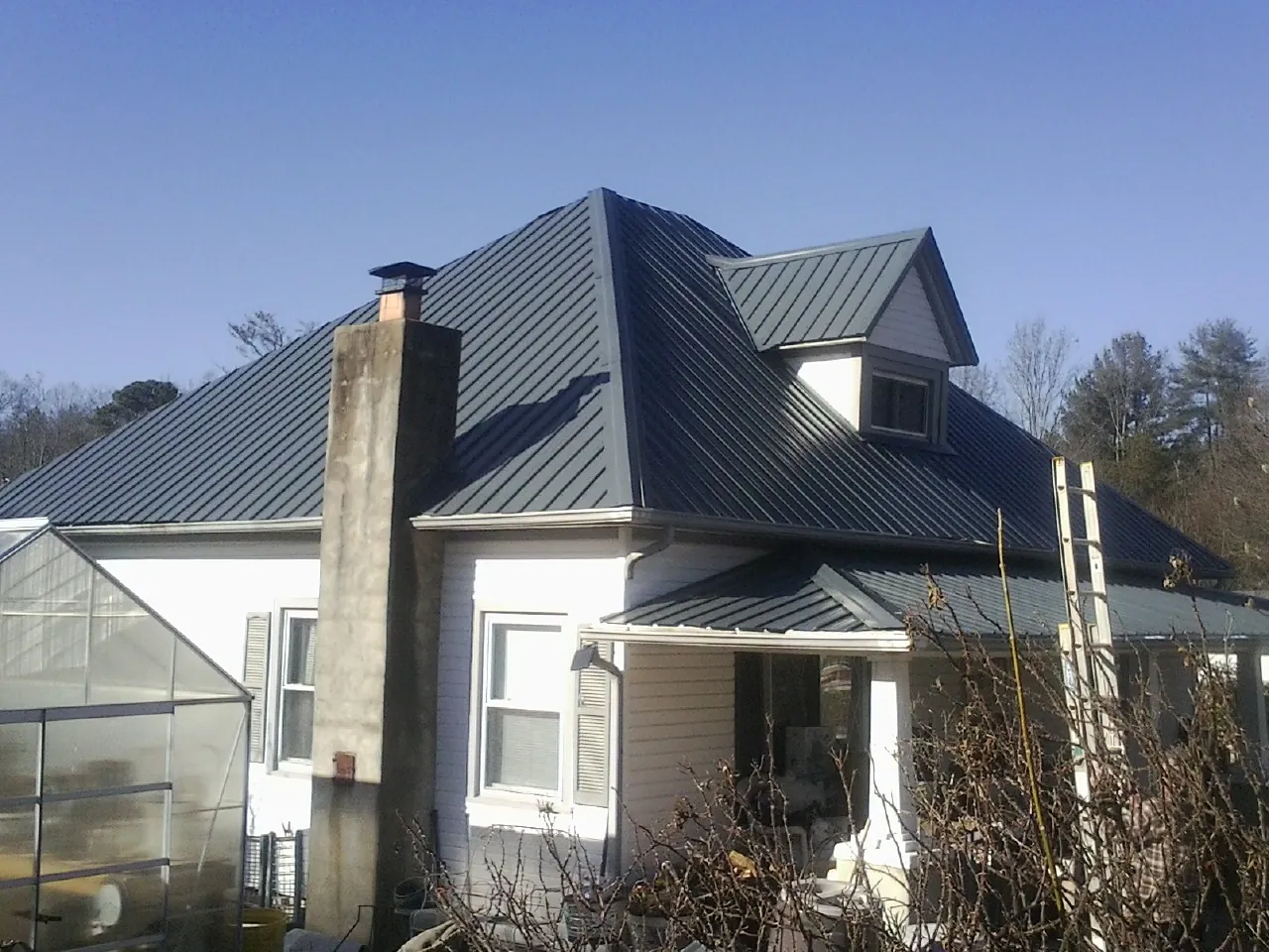 Dark blue standing seam metal roof on a white farmhouse with dormer — Slate & Tile Roof Repair by Roofing Brothers in Somerville