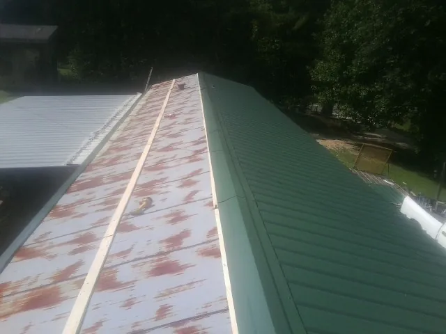 Old rusted panels beside newly installed green metal roofing — Wind Damage Roof Repair by Roofing Brothers in Somerville