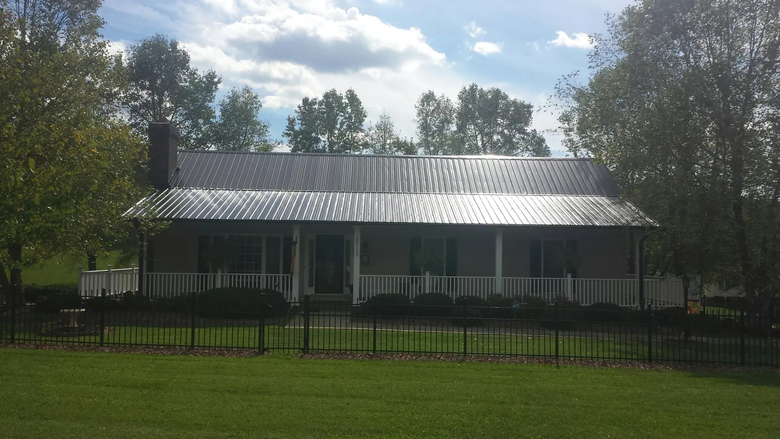 Gray metal roof on a brick ranch with a full width front porch — Gutter Guard Installation work by our crew in Somerville